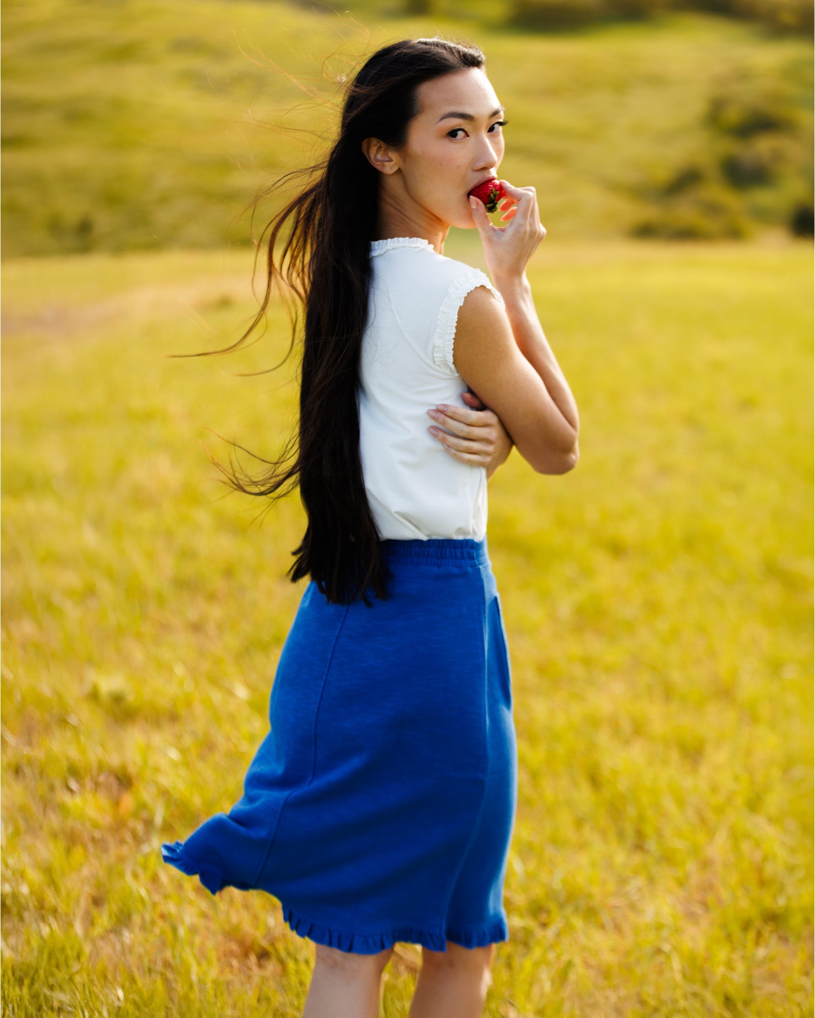 Woman wearing a white top and blue skirt in the middle of a field