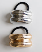 Two metallic hair ties, one silver and one gold, on a white background.