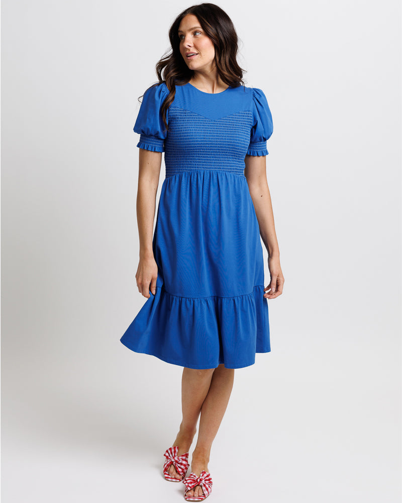 Model wearing a classic blue short sleeve midi dress with smocking across bodice