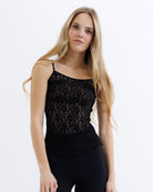 Woman wearing a black lace top against a white background