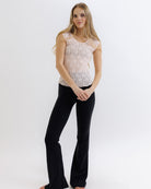 Woman wearing a lace top and black pants on a white background