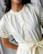 Close-up of a person wearing a light yellow dress with lace details.