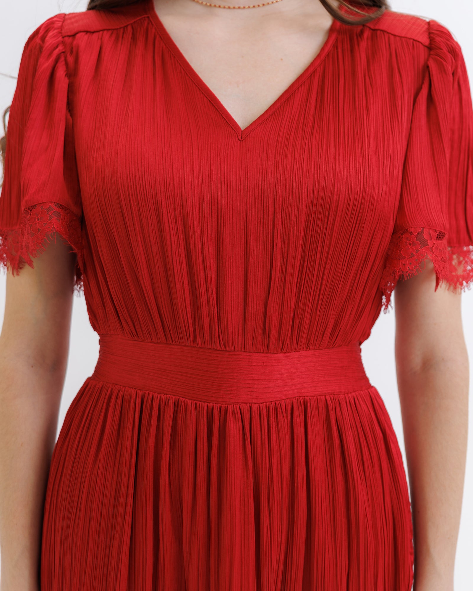 Red pleated dress with lace details on a white background