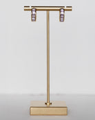 Gold earring stand with hoop earrings on a light gray background