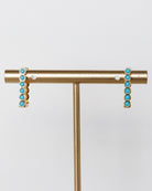 Gold earrings with turquoise stones on a white background