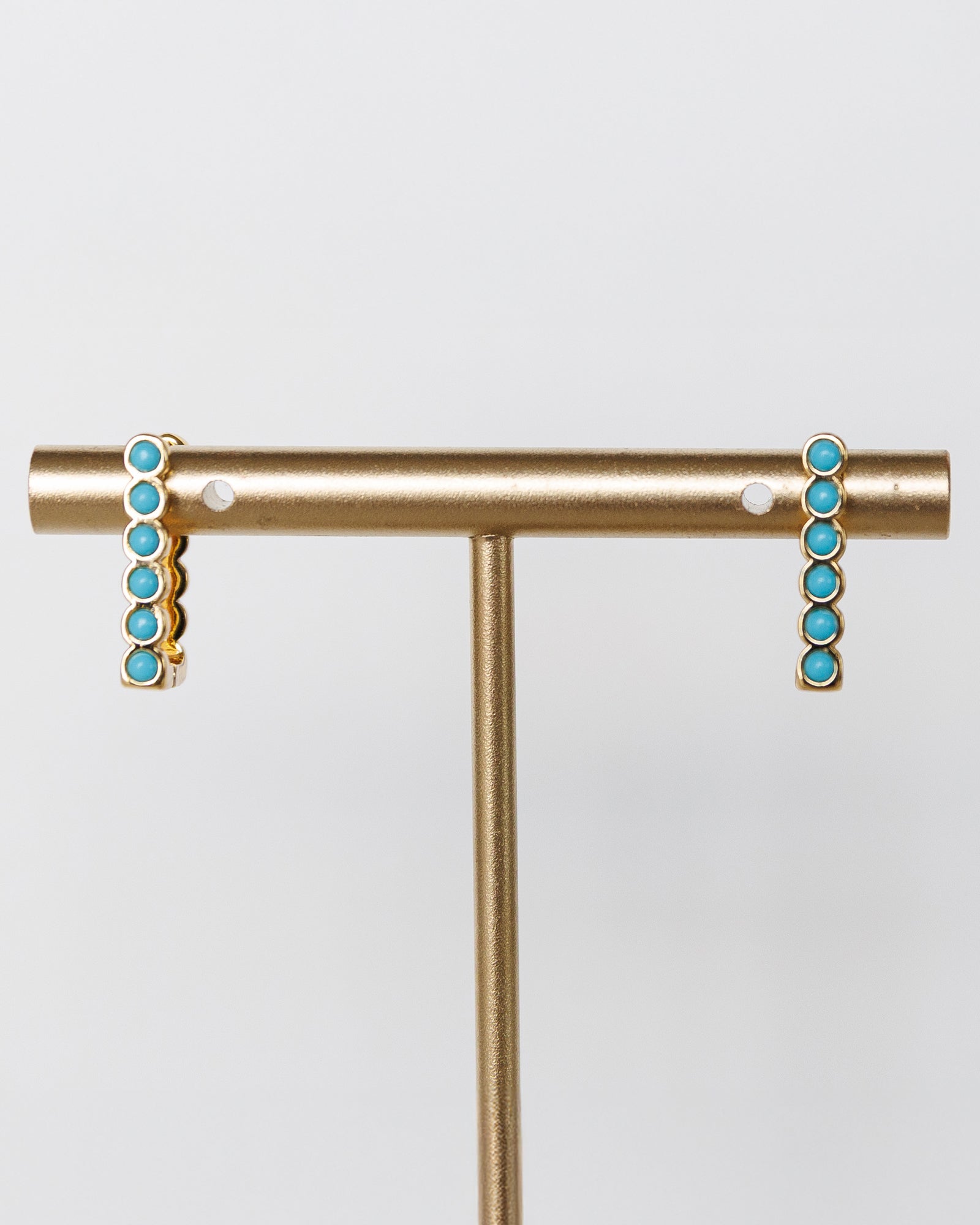 Gold earrings with turquoise stones on a white background