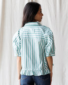 Woman wearing a green and white striped shirt against a white background
