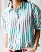 Person wearing a green and white striped shirt with a plain background