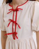 Beige dress with red bows on a plain background