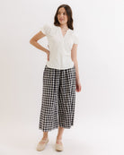 Woman wearing a white blouse and black checkered pants on a white background