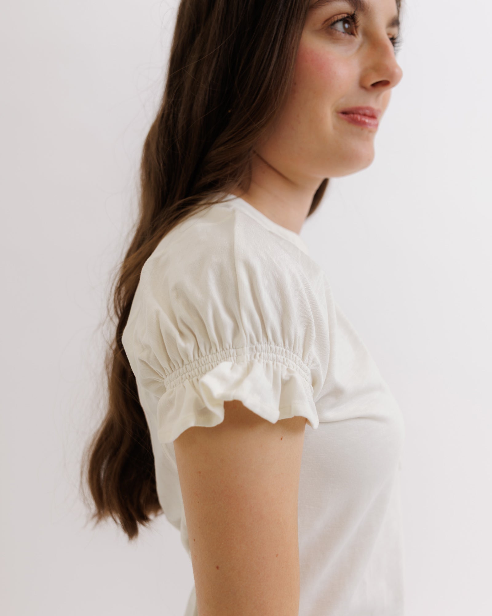 Woman wearing a white blouse against a plain background