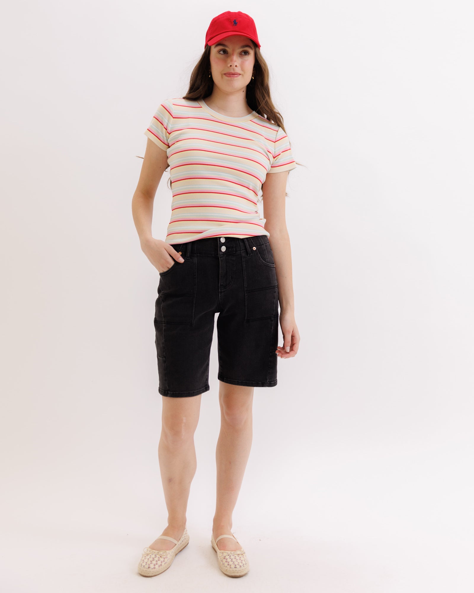 Person wearing a striped shirt, black shorts, and a red cap on a white background