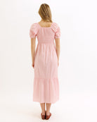 Woman wearing a pink dress with puff sleeves on a white background