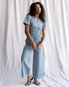 Woman wearing a blue and white checkered jumpsuit against a white background