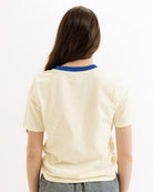Person wearing a beige t-shirt with a blue collar on a white background