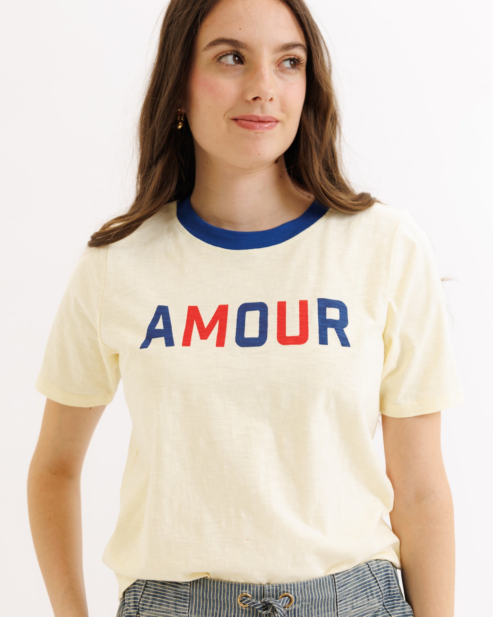 Woman wearing a cream t-shirt with 'AMOUR' in red and blue letters on a white background