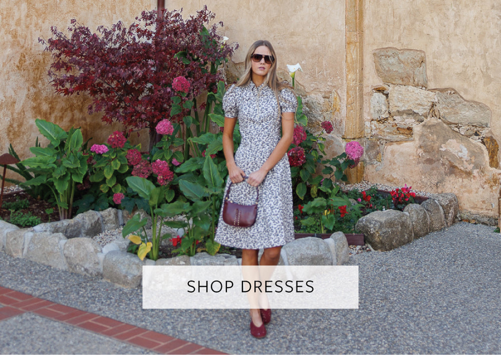 Woman in an animal print dress standing in front of flowers with 'Shop Dresses' text overlay.