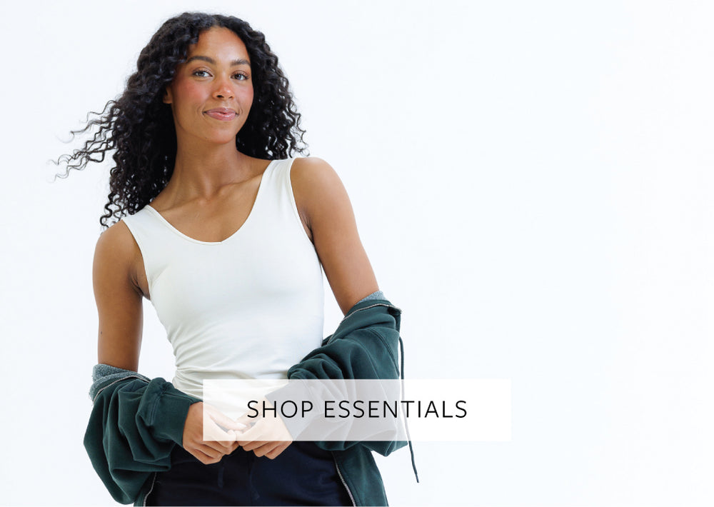 Woman in a white top and green sweatshirt with text 'Shop Essentials' on a white background