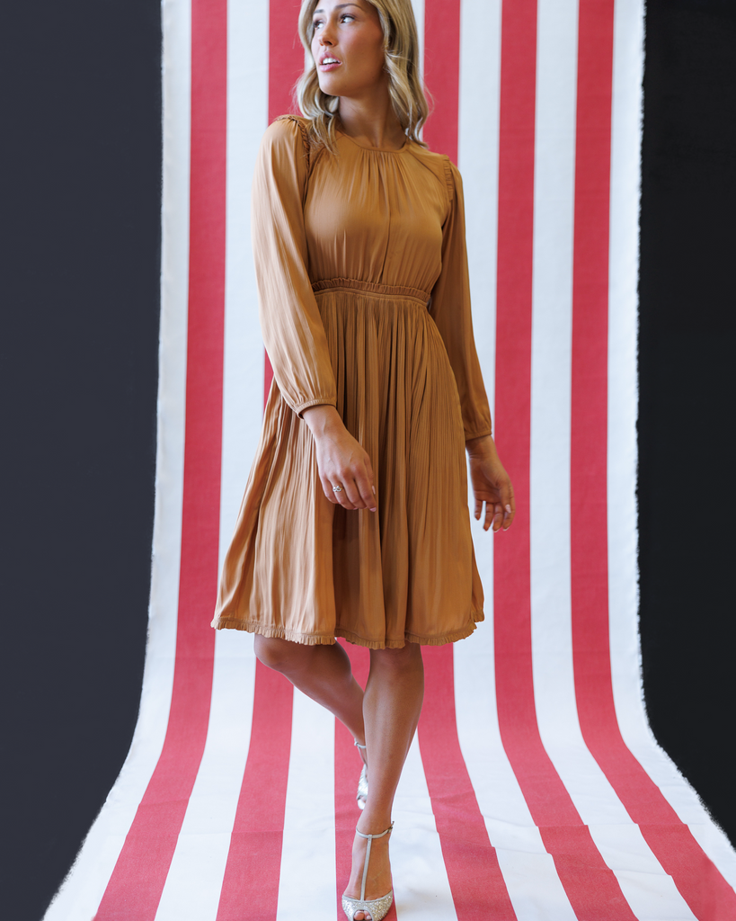 Woman wearing an orange knee-length dress on a striped background