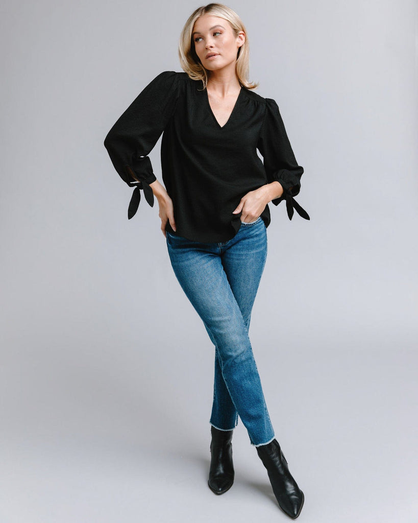 Woman in a long sleeve, v-neck, black blouse