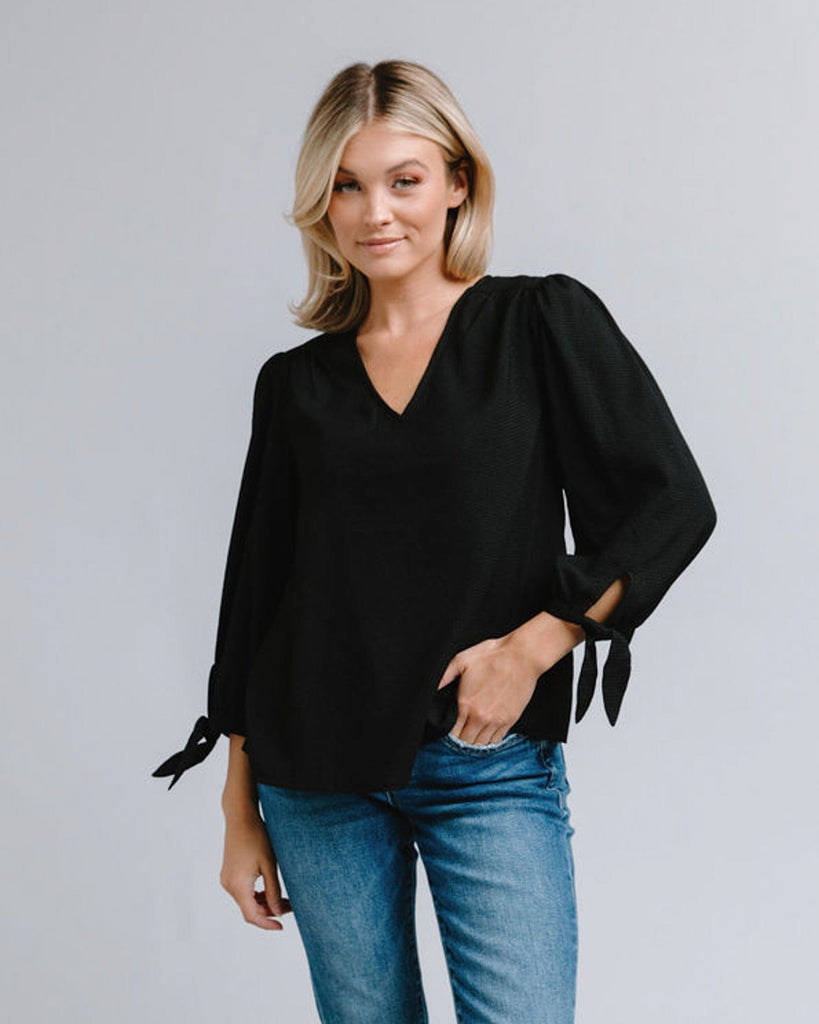 Woman in a long sleeve, v-neck, black blouse