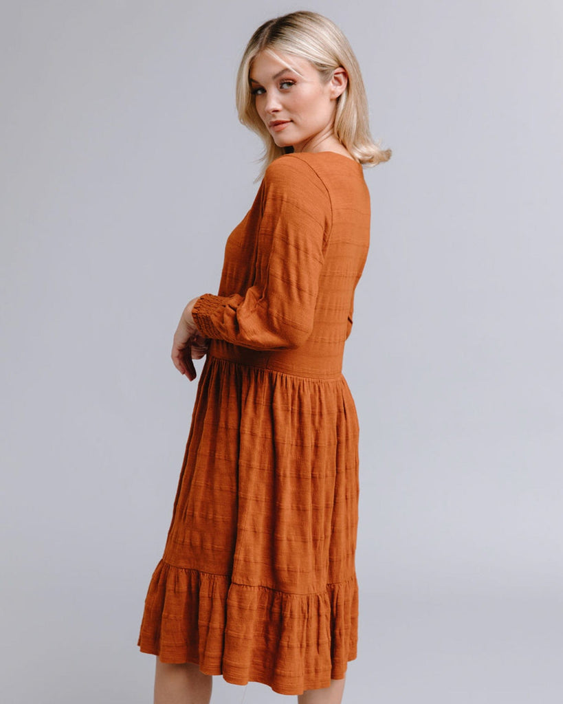 Woman in a long sleeve, button-down, orange dress