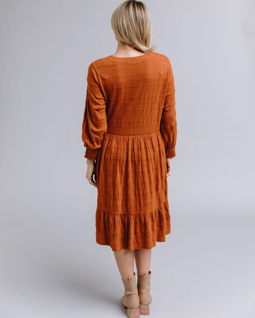 Woman in a long sleeve, button-down, orange dress