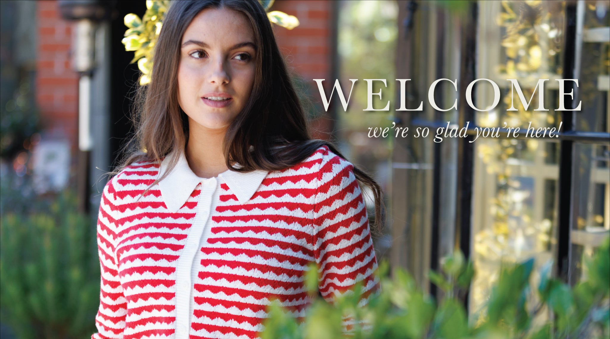 Woman wearing a red and white striped jacket with a 'WELCOME' message in the background.