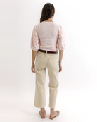 Woman wearing a light pink top and beige pants on a white background