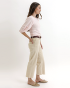 Woman wearing a light pink top and beige pants on a white background