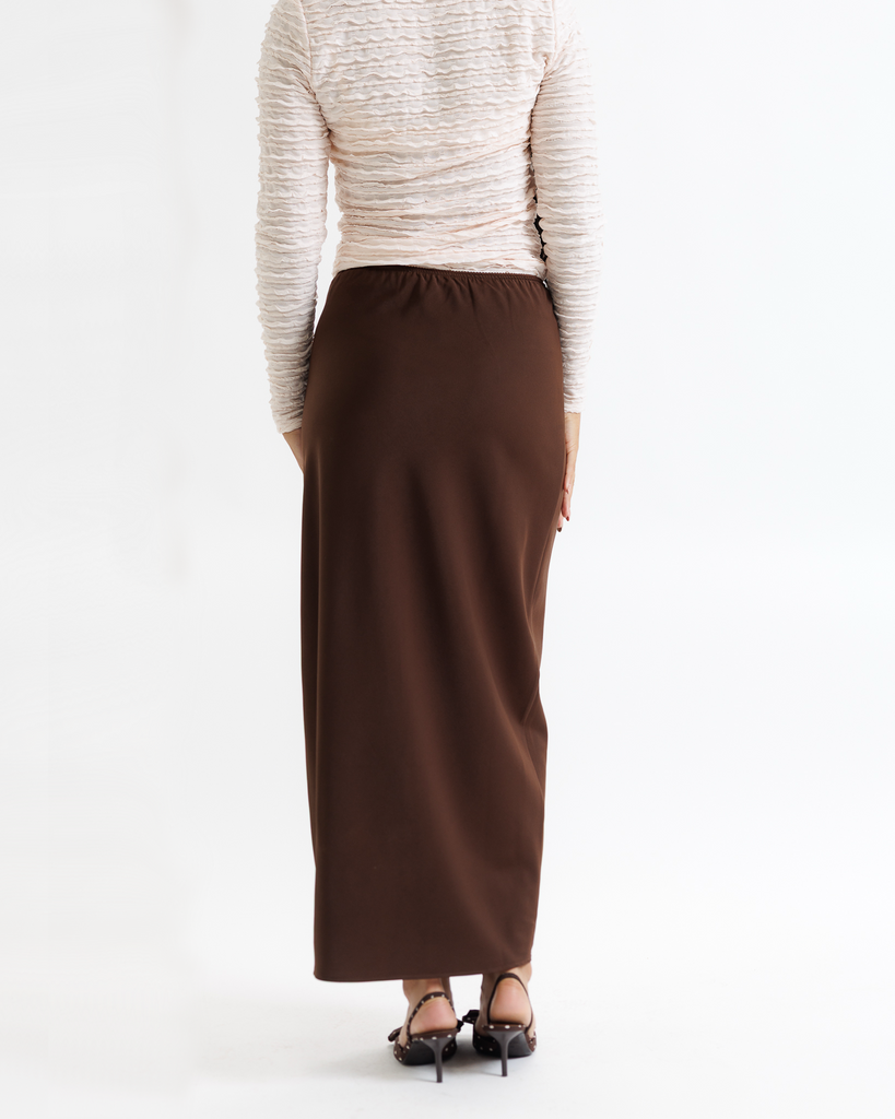 Woman wearing a white top and brown skirt on a white background