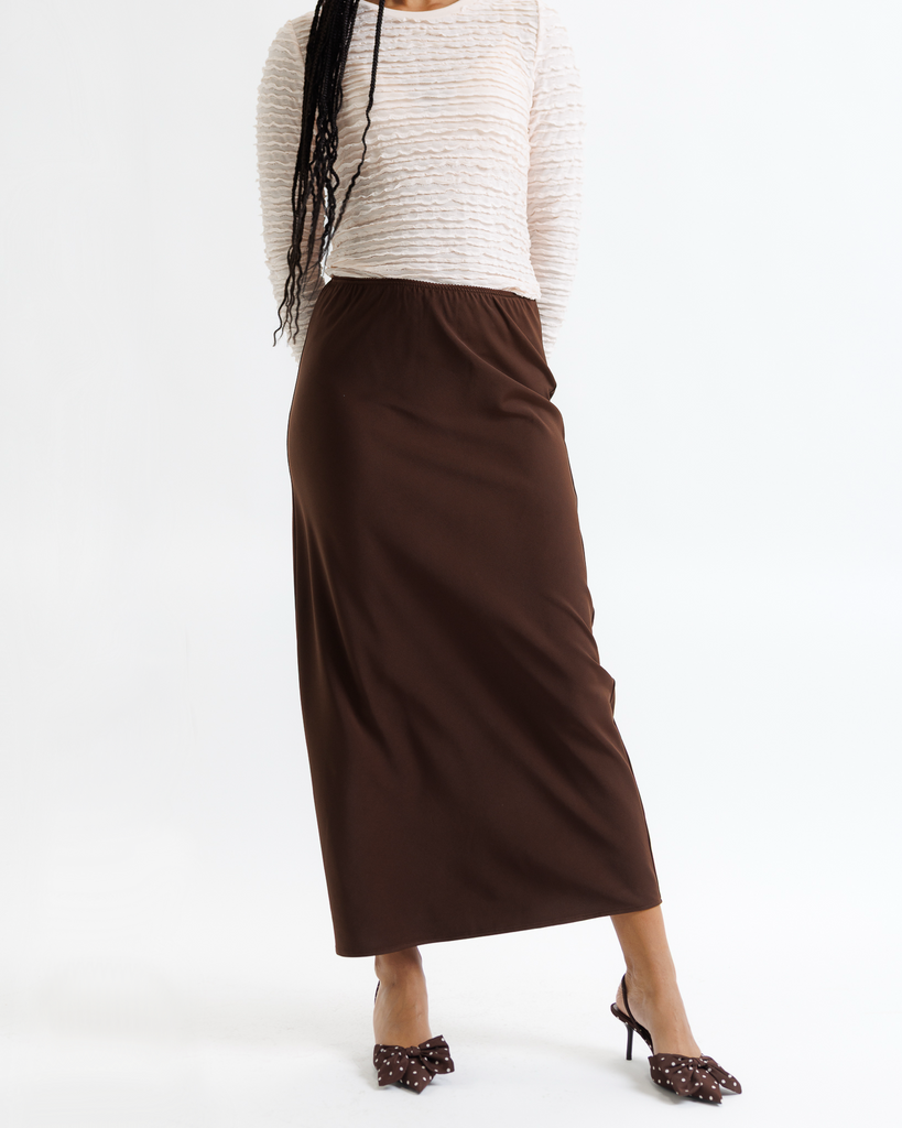 Woman wearing a white top and brown skirt on a white background