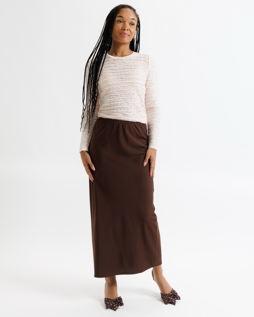 Woman wearing a white top and brown skirt on a white background