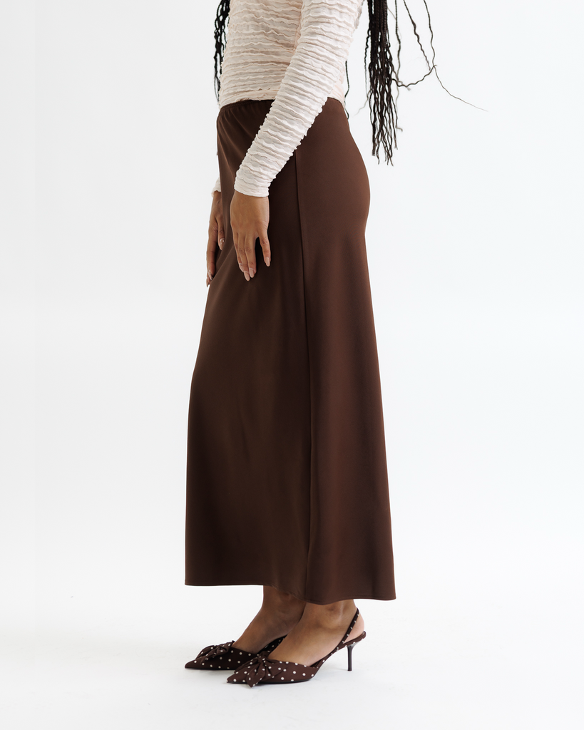 Woman wearing a white top and brown skirt on a white background