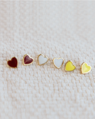 Set of heart-shaped earrings in various colors on a textured cream fabric