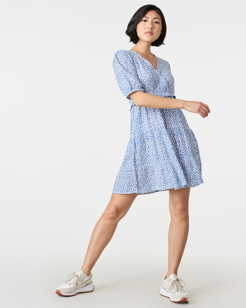 Woman in a short sleeve, mini dress that is blue and white with a v-neckline