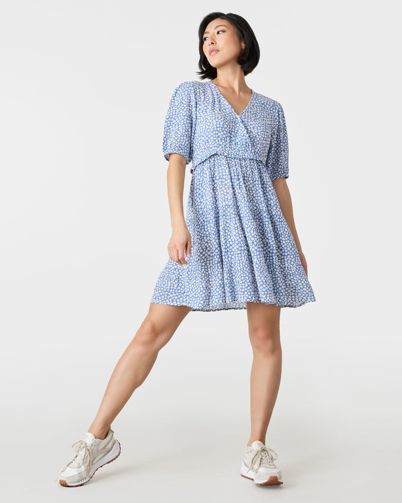 Woman in a short sleeve, mini dress that is blue and white with a v-neckline