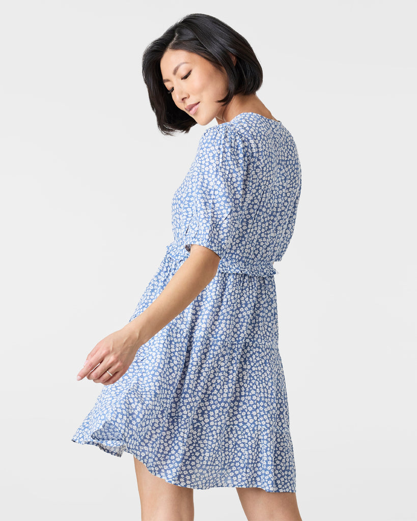 Woman in a short sleeve, mini dress that is blue and white with a v-neckline