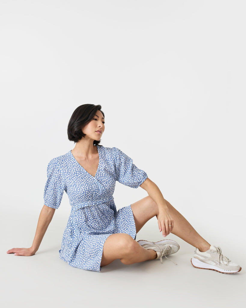 Woman in a short sleeve, mini dress that is blue and white with a v-neckline