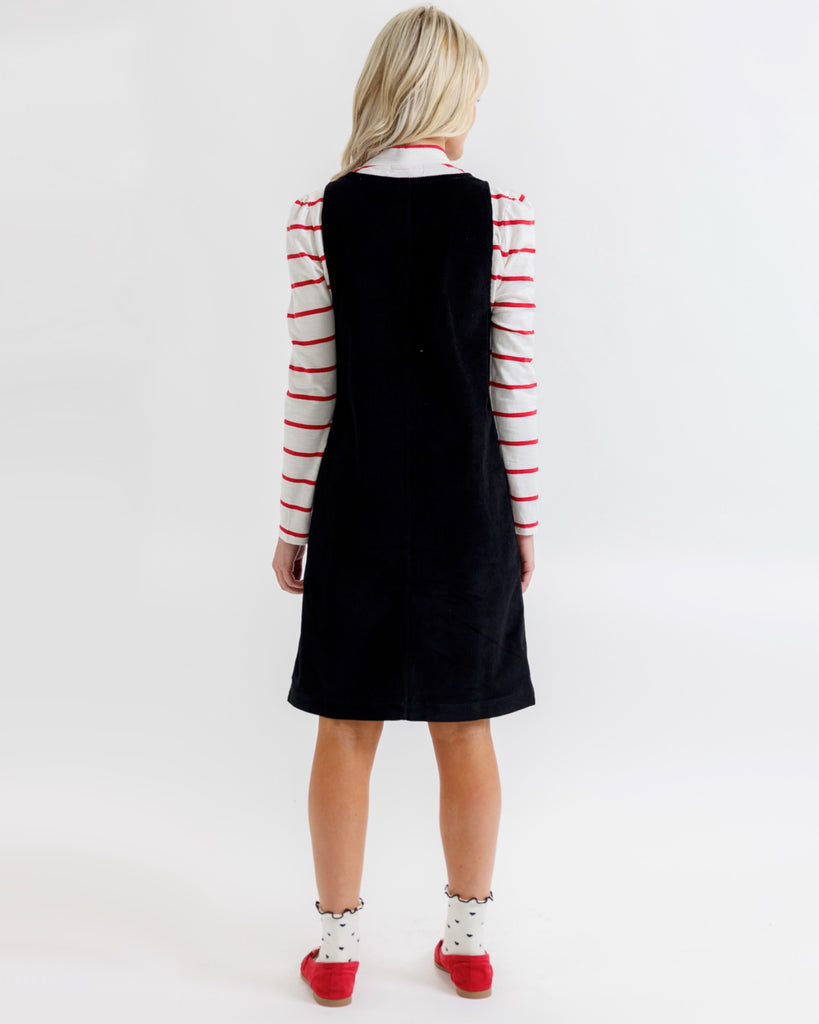 Person wearing a black dress with red and white striped sleeves on a white background