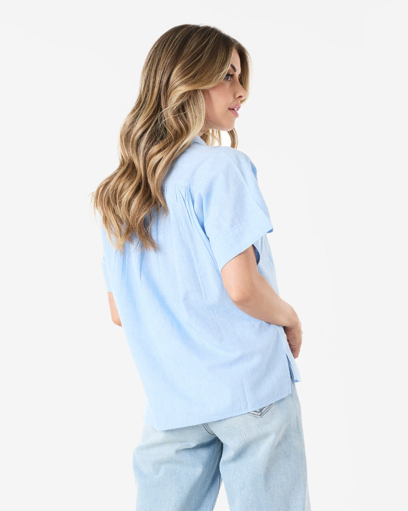 Back view of woman in a blue short sleeved, collared, button-down