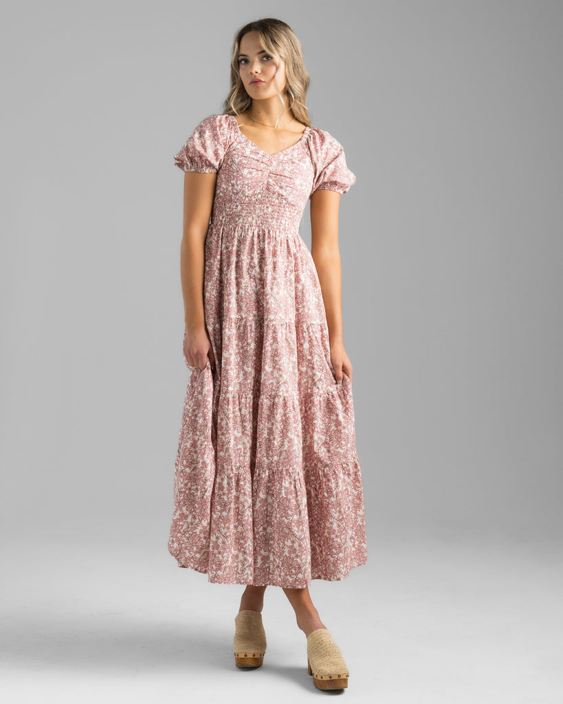 Model wearing a pink floral print, short sleeve, sweetheart neckline with smocked bodice, midi-length dress.