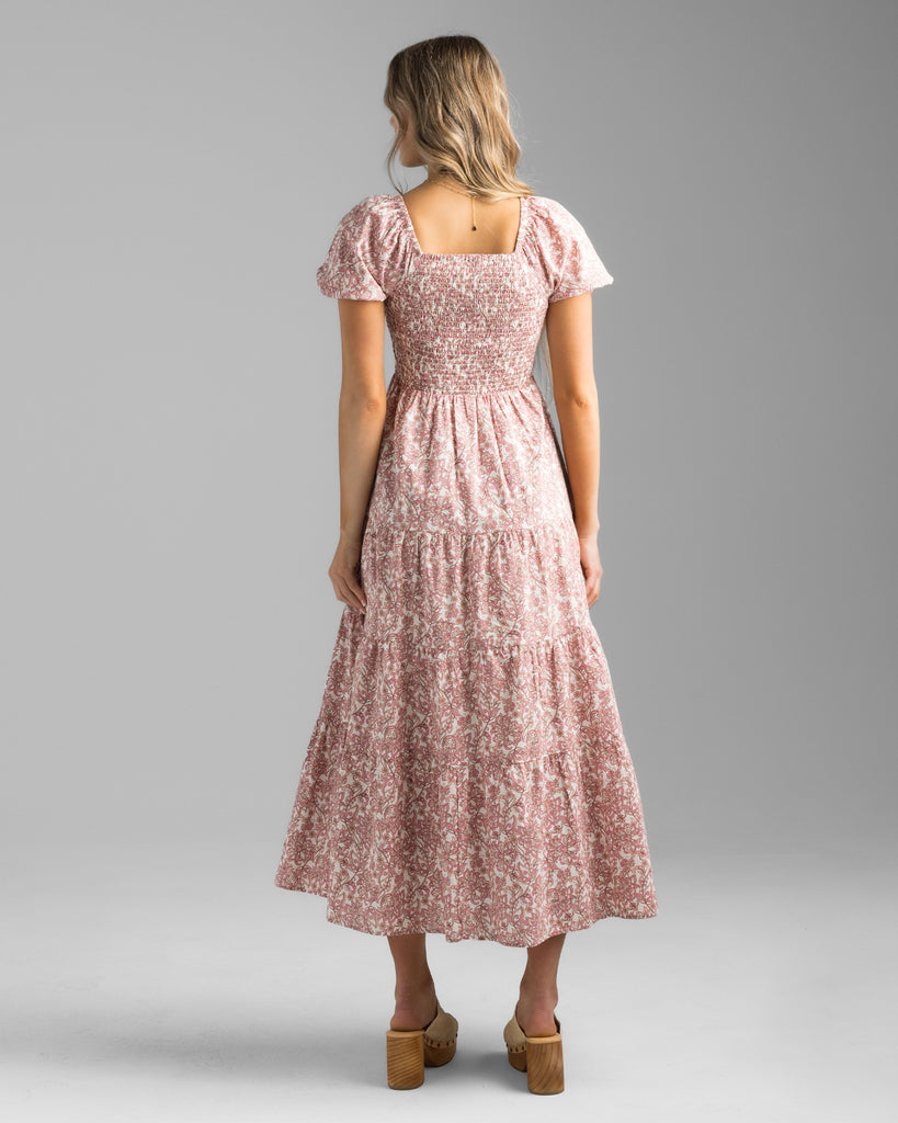 Model wearing a pink floral print, short sleeve, sweetheart neckline with smocked bodice, midi-length dress.