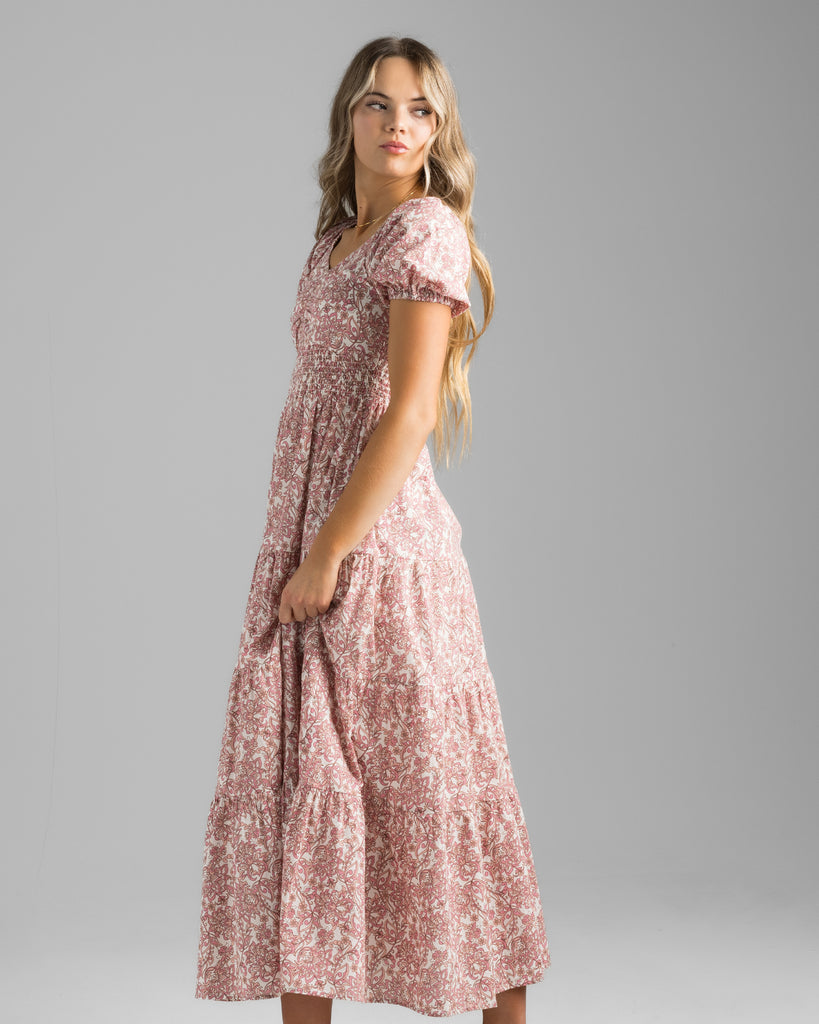 Model wearing a pink floral print, short sleeve, sweetheart neckline with smocked bodice, midi-length dress.