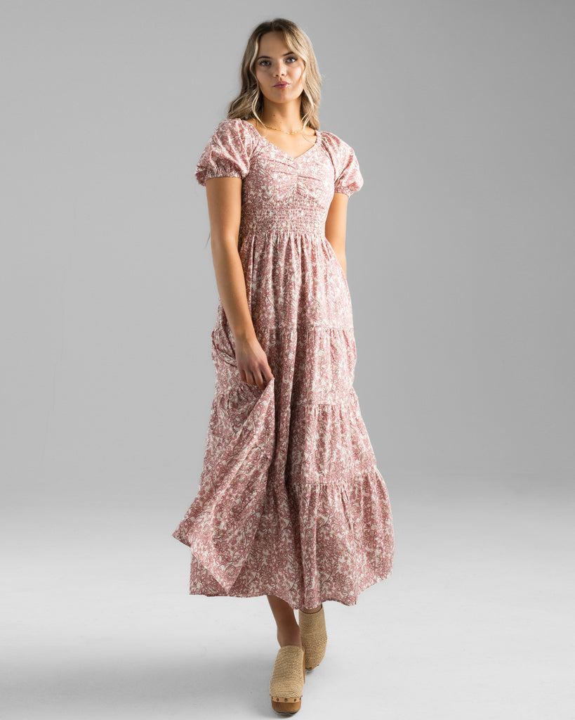 Model wearing a pink floral print, short sleeve, sweetheart neckline with smocked bodice, midi-length dress.