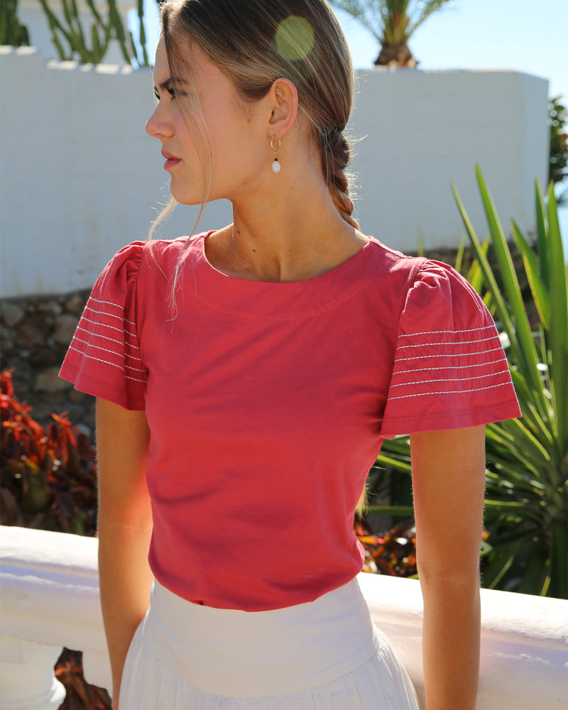 Model wearing a red round neck short sleeve t-shirt with stitching on arms