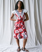 Woman wearing a red floral dress with white and black accents against a plain background