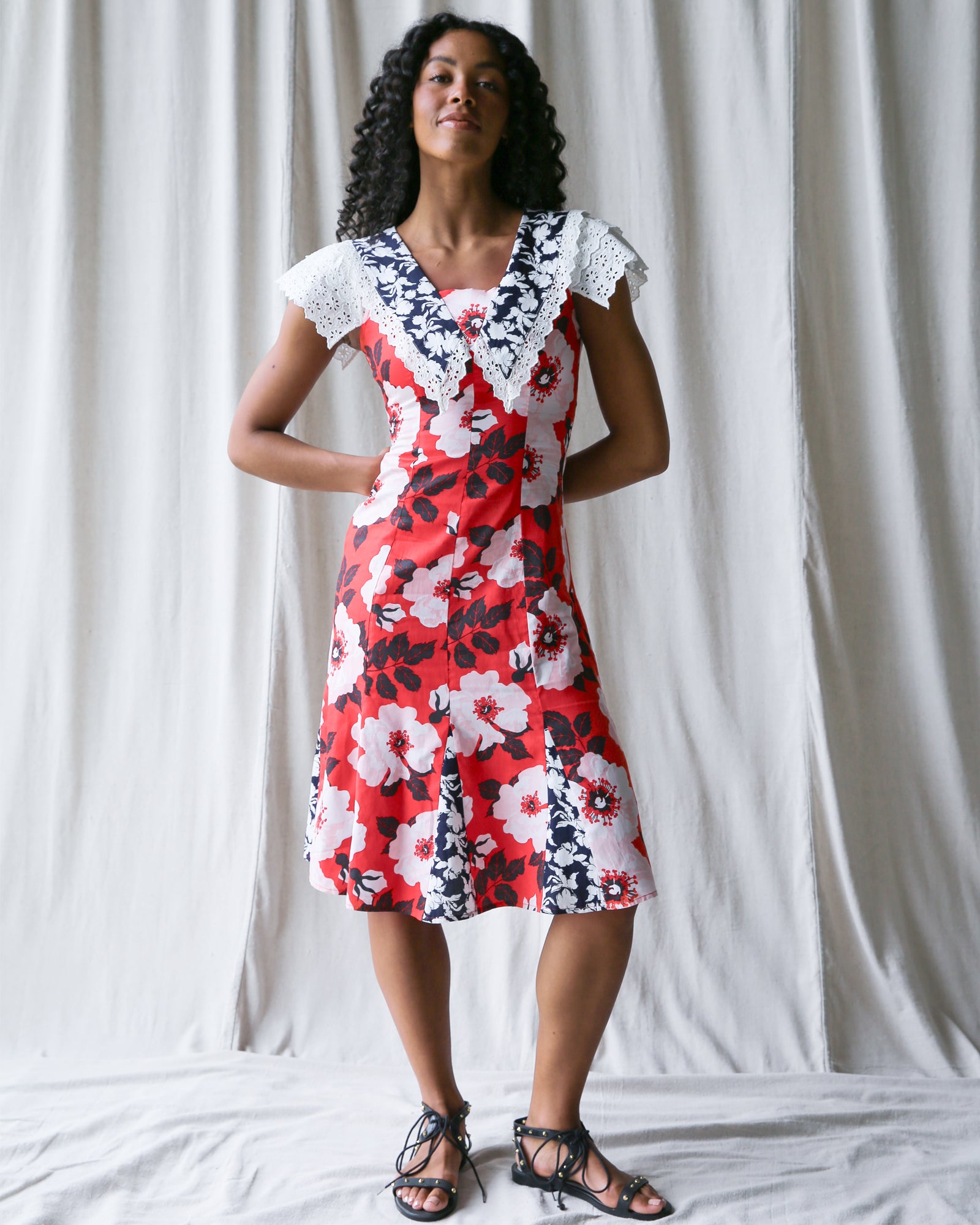 Woman wearing a red floral dress with white and black accents against a plain background