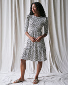 Woman wearing a black and white patterned dress standing against a plain background