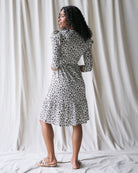Woman wearing a black and white patterned dress against a plain background